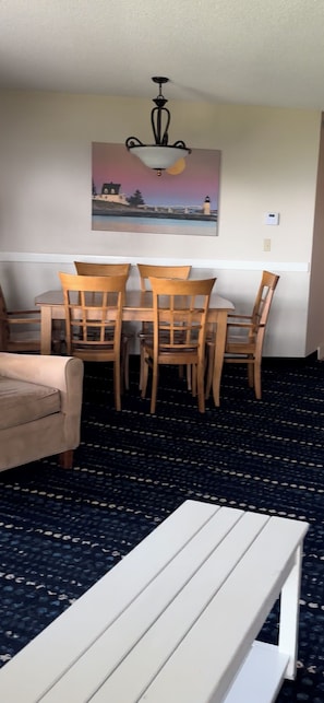 A dining area with a table and chairs, a bench, and a ceiling light fixture.