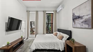 Une chambre moderne avec un lit, une télévision, un tableau et une fenêtre avec des rideaux.