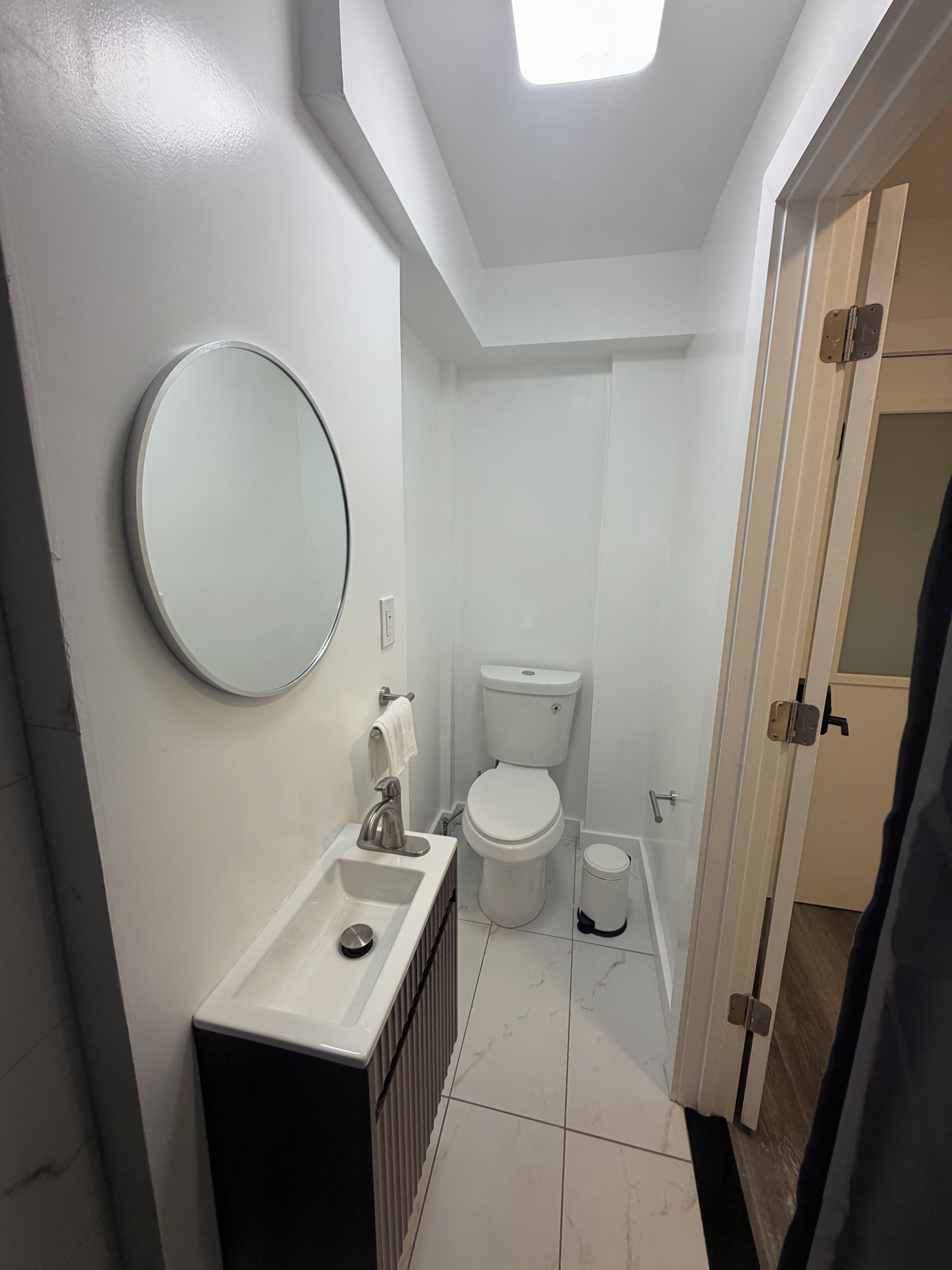 Ein kleines Badezimmer mit Toilette, Waschbecken und Spiegel.