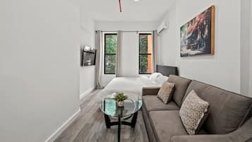 Une chambre d’hôtel moderne, équipée d’un lit, d’un canapé, d’une table basse en verre et d’un tableau au mur.