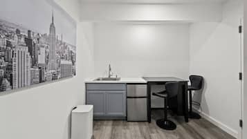 A compact kitchen with a sink, a refrigerator, and a dining area with a chair.