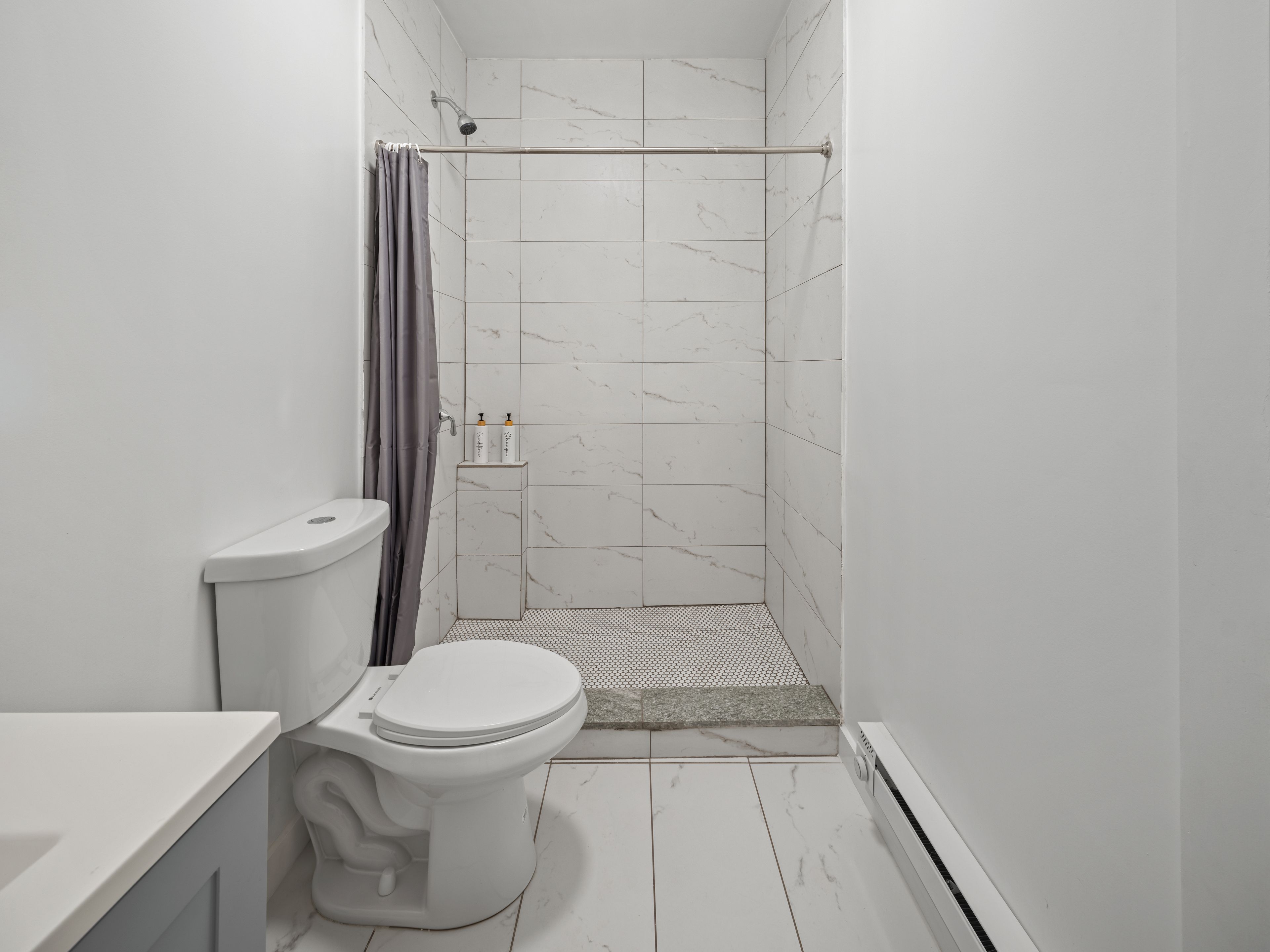 Une salle de bain avec des toilettes, une douche et des murs carrelés.