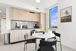 Eine moderne Küche mit Holzausstattung, einem runden Esstisch und Blick auf die Stadt durch ein großes Fenster.