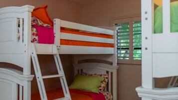 A bunk bed with a ladder, a ceiling fan, and a window with blinds.