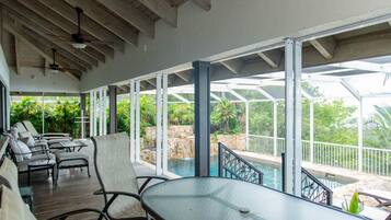 A covered outdoor area with a pool, lounge chairs, and a table.