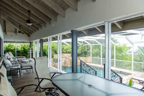A covered outdoor area with a pool, lounge chairs, and a table. - Coral Sunset in Islamorada (Tavernier)