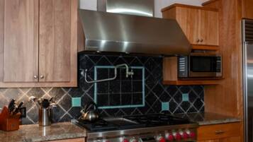 A kitchen with wooden cabinets, a stainless steel range hood, a microwave, and a double oven.