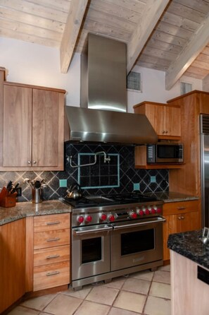 A kitchen with wooden cabinets, a stainless steel range hood, a microwave, and a double oven. - Coral Sunset in Islamorada (Tavernier)