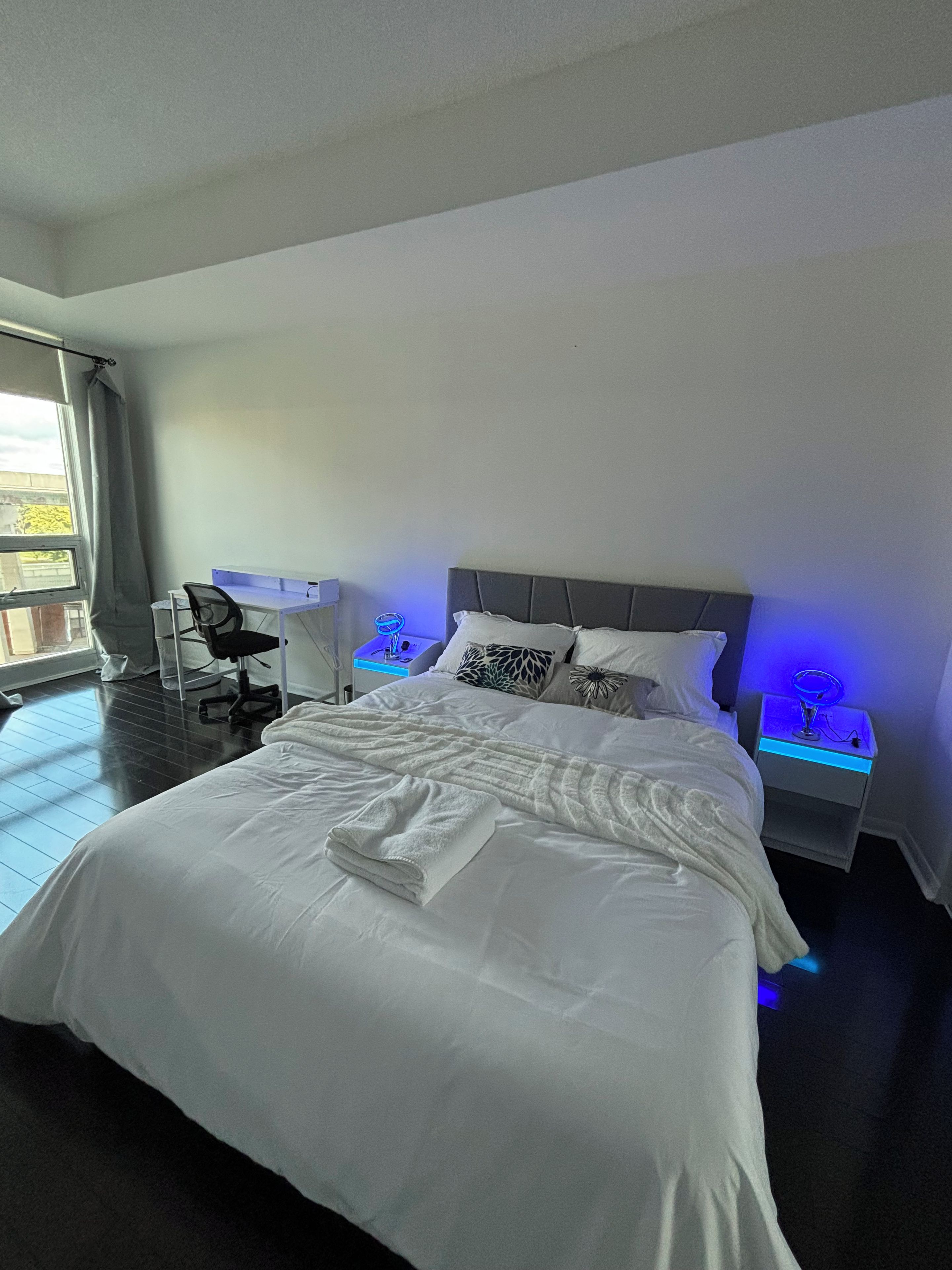 Ein Hotelzimmer mit einem großen Bett, einem Schreibtisch und einem Stuhl. Es gibt zwei Nachttische mit Lampen.