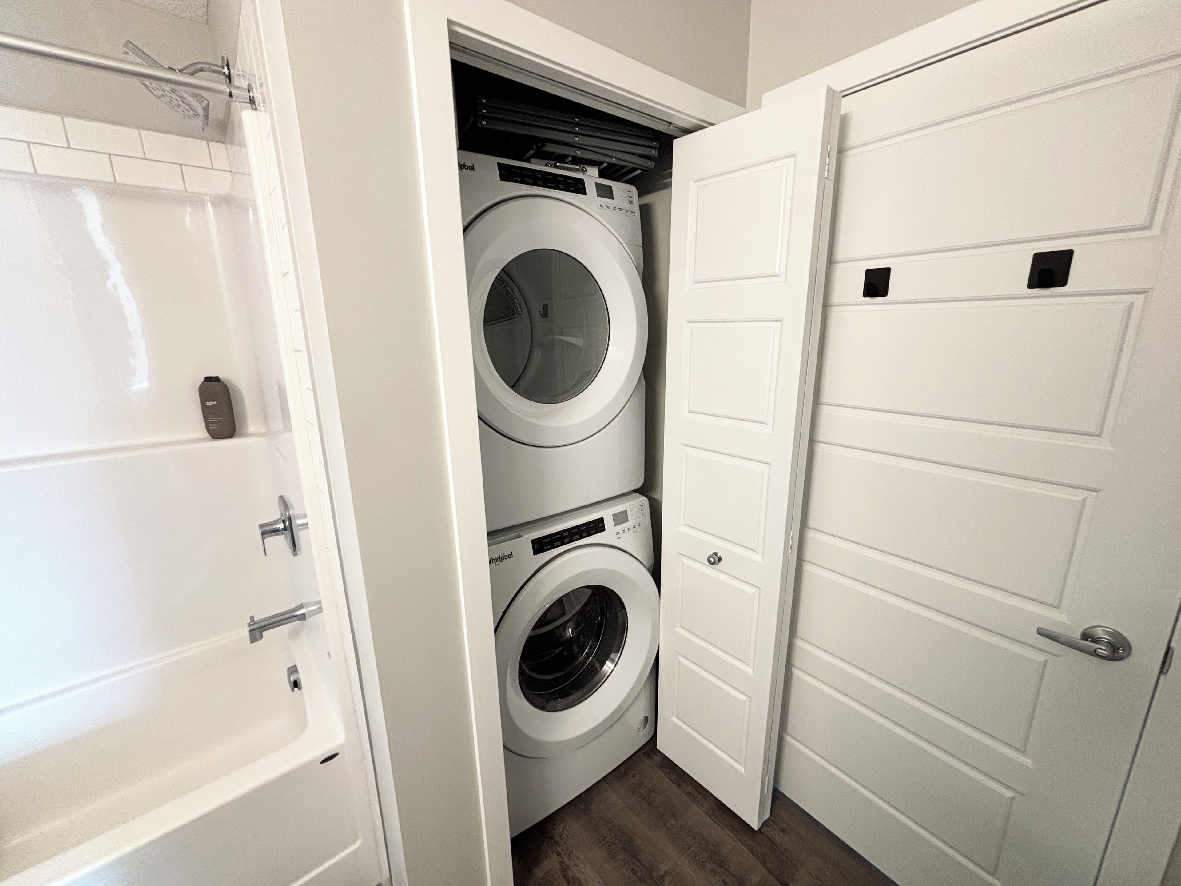 A laundry room with two stacked front-loading washing machines and a white door.