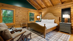 Un dormitorio de cabaña con una cama de madera, una silla, una mesita de noche y un aparador.