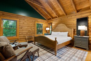 A log cabin bedroom with a wooden bed, a chair, a nightstand, and a dresser.