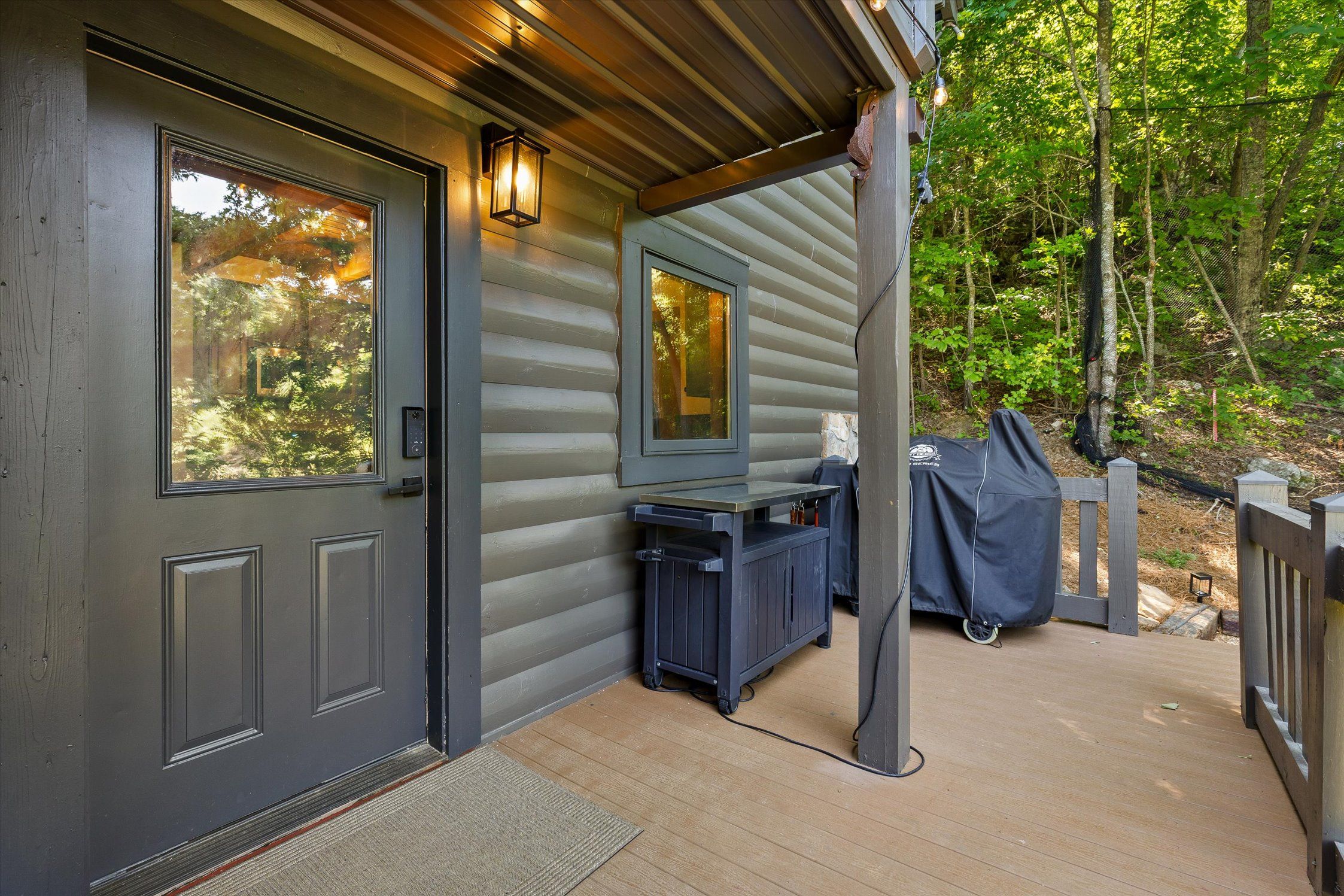 Une cabane en bois avec une porte d’entrée, un petit porche et un espace extérieur abrité avec des sièges.