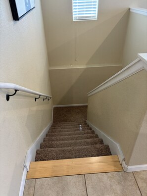 A carpeted staircase with a wooden handrail and a small window at the top.