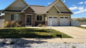 A two-story house with a stone facade, a front entrance, and a garage with two doors.
