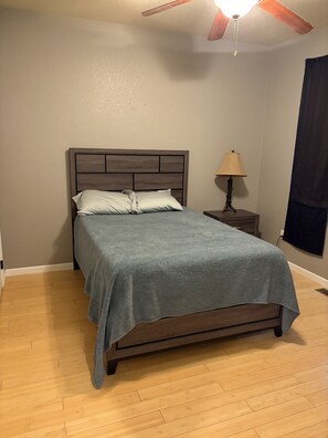 A bedroom with a bed, a nightstand, a lamp, and a ceiling fan.