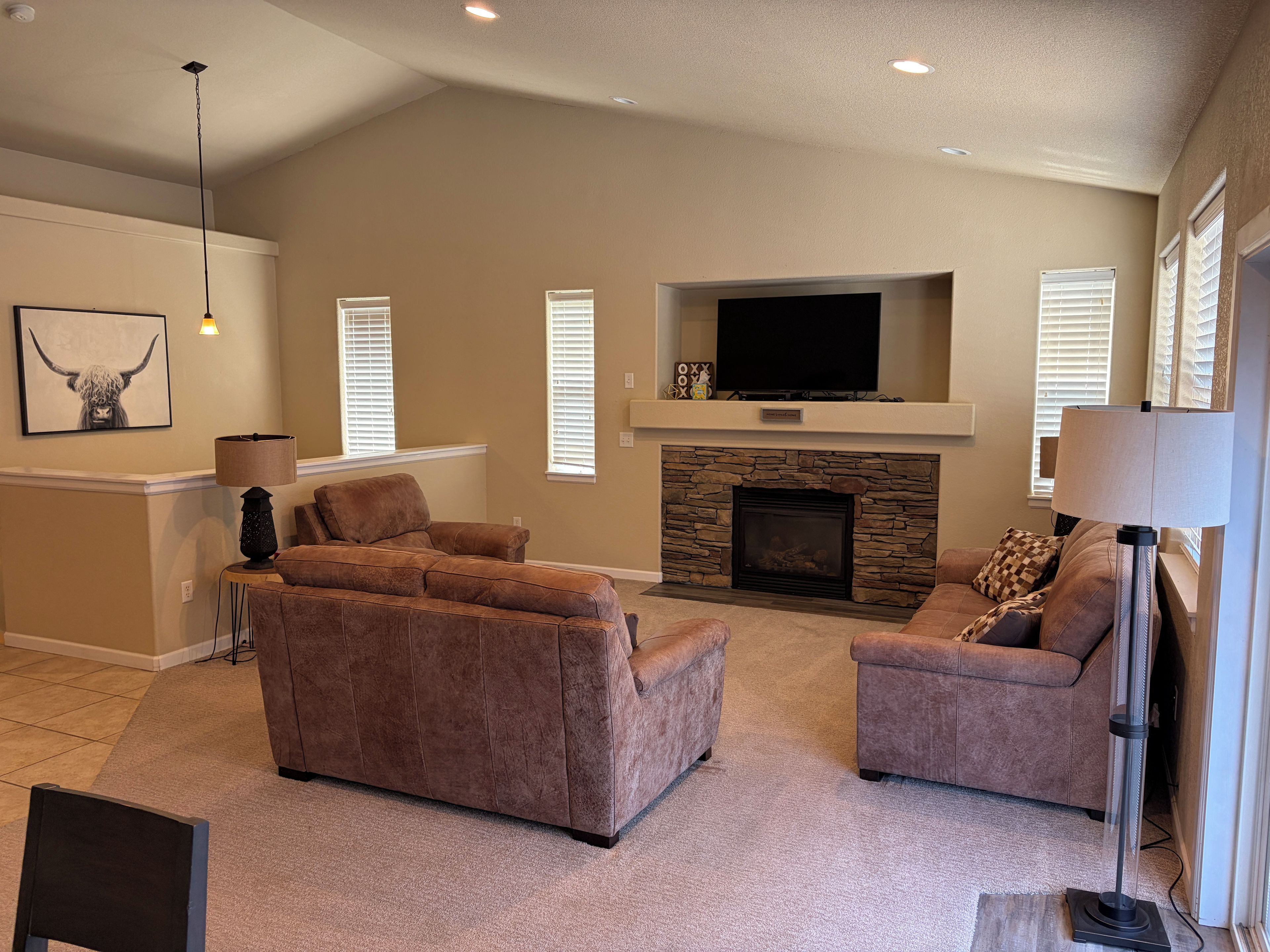 A living room with a fireplace, two sofas, a television, and a lamp.
