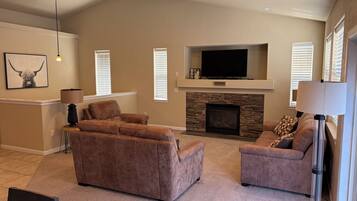 A living room with a fireplace, two sofas, a television, and a lamp.