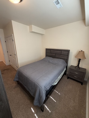 Una camera da letto con un letto, un comodino, una lampada e una porta.