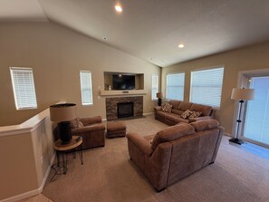 A living room with a stone fireplace, a flat-screen TV, and a sectional sofa.