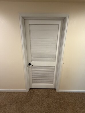 A closed door with a horizontal louvered panel and a doorknob.
