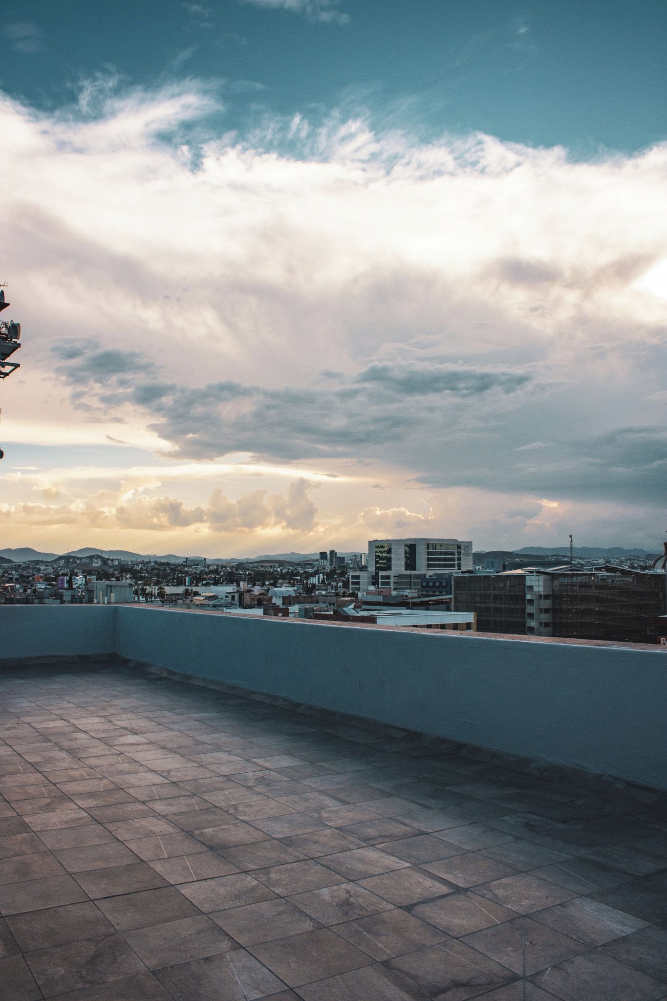 Una terraza en la azotea con vistas a un paisaje urbano y nubes.