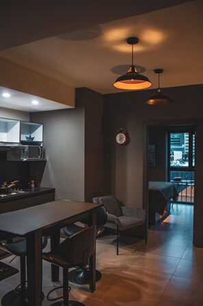 A modern kitchen with a microwave, a clock, and a dining area with a table and chairs.