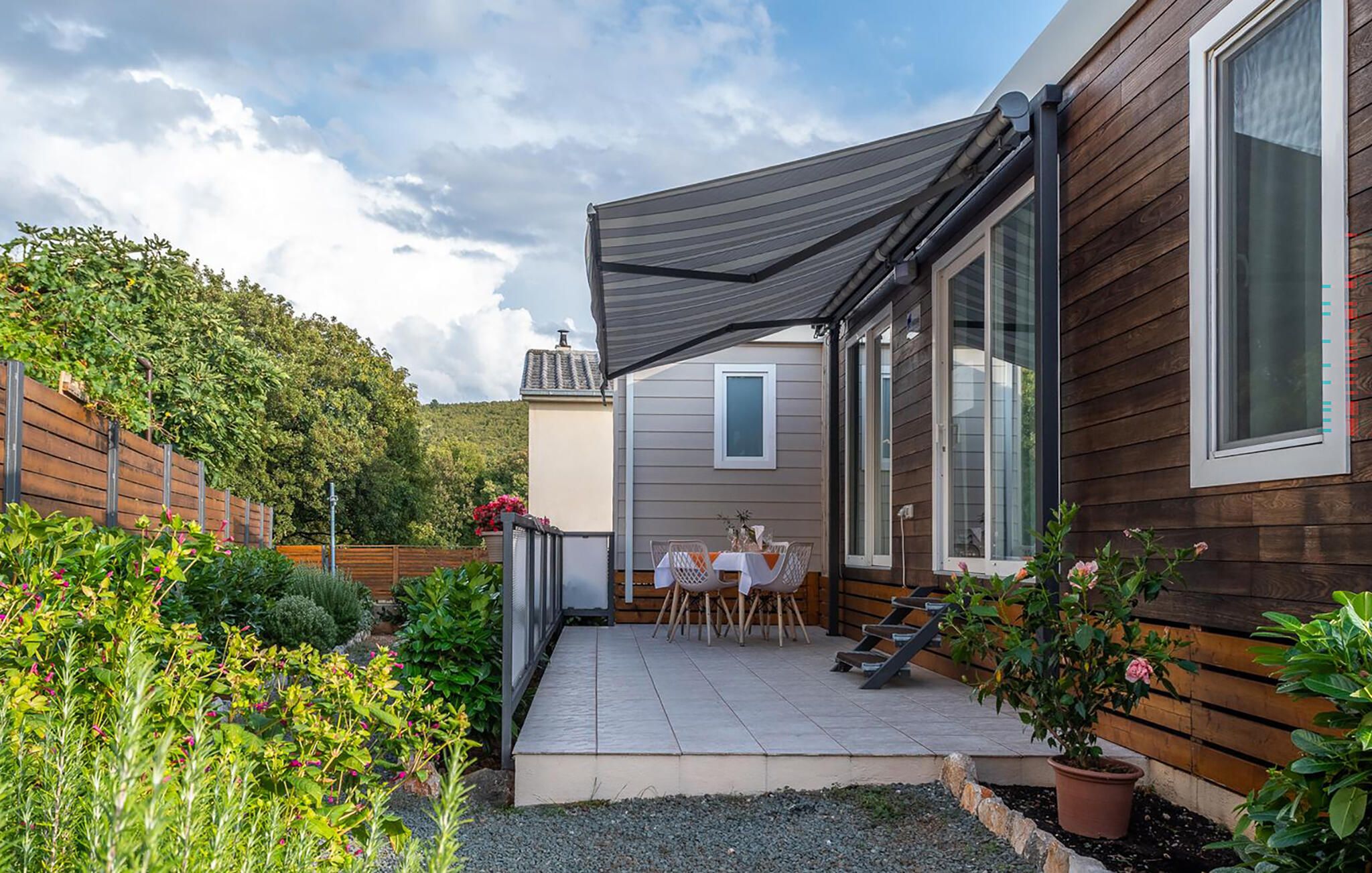 Un espace patio aménagé avec une table et des chaises, une clôture en bois et un jardin où poussent différentes plantes.