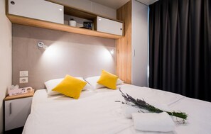 A hotel room with a bed, two pillows, a nightstand, a lamp, a shelf with decorative items, and a window with curtains. - Cozy apartment in Donji Zagon with WiFi (Donji Zagon)