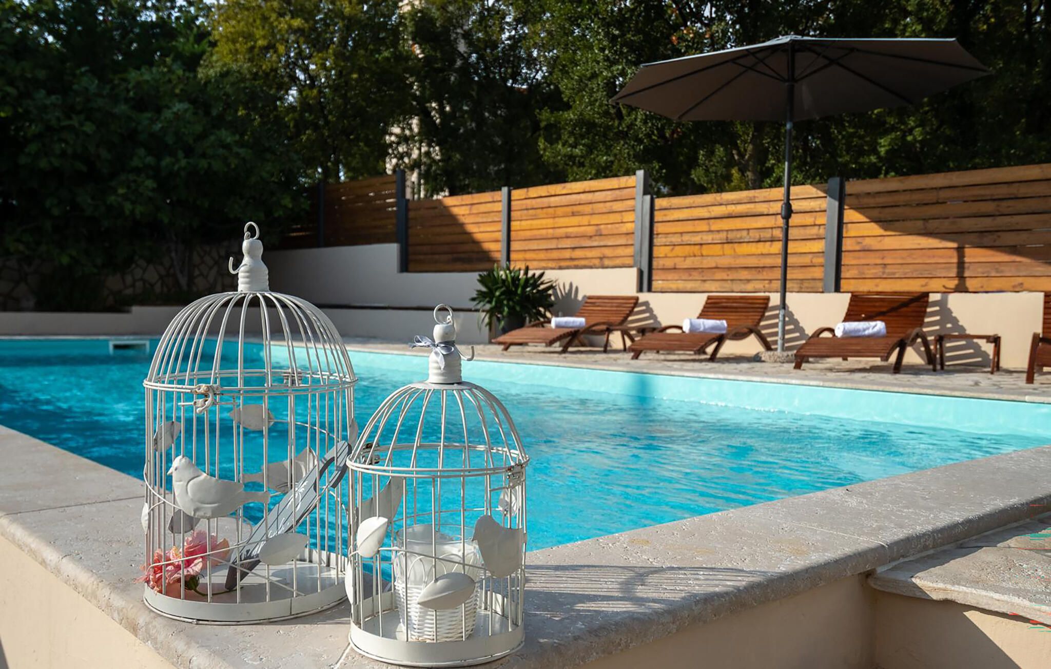 Une piscine agrémentée de deux volières et de chaises longues.