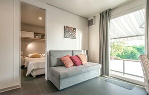 A modern bedroom with a grey sofa, a bed, and a large window with curtains. - Beautiful apartment in Donji Zagon with WiFi (Donji Zagon)