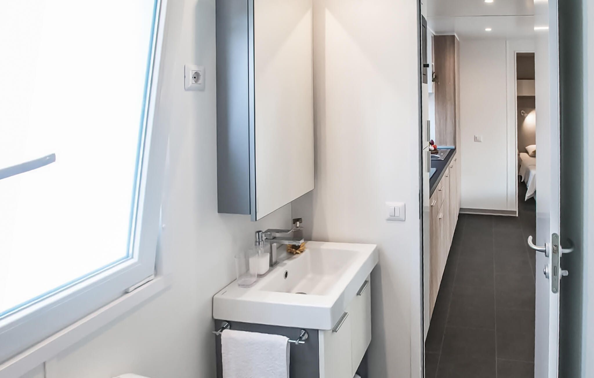 Ein modernes Badezimmer mit Waschbecken, Spiegel und Handtuchhalter.