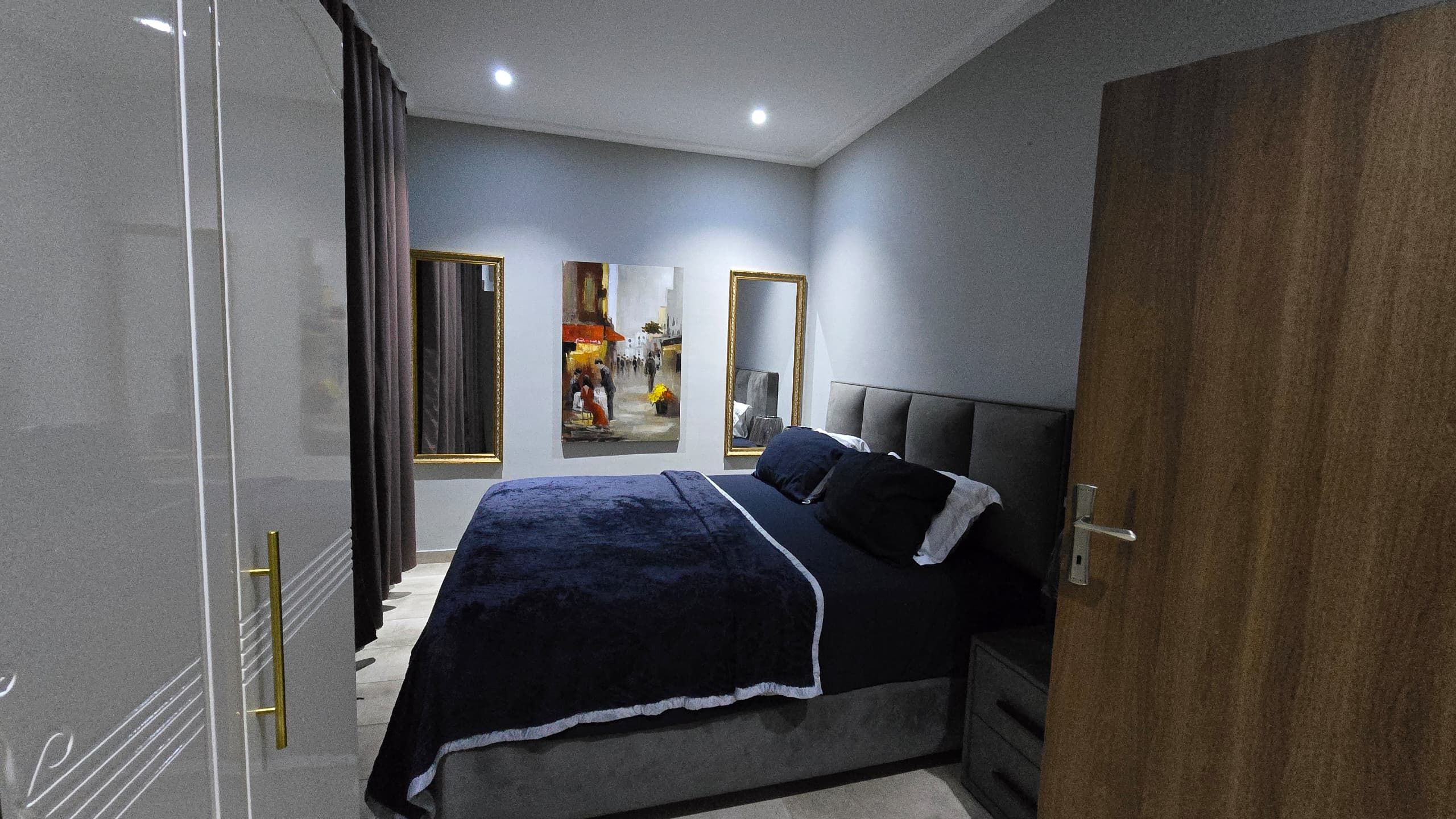 A bedroom with a bed, a wardrobe, a mirror, and a door.