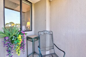 Un balcone con una sedia, un tavolino e una composizione floreale pensile.