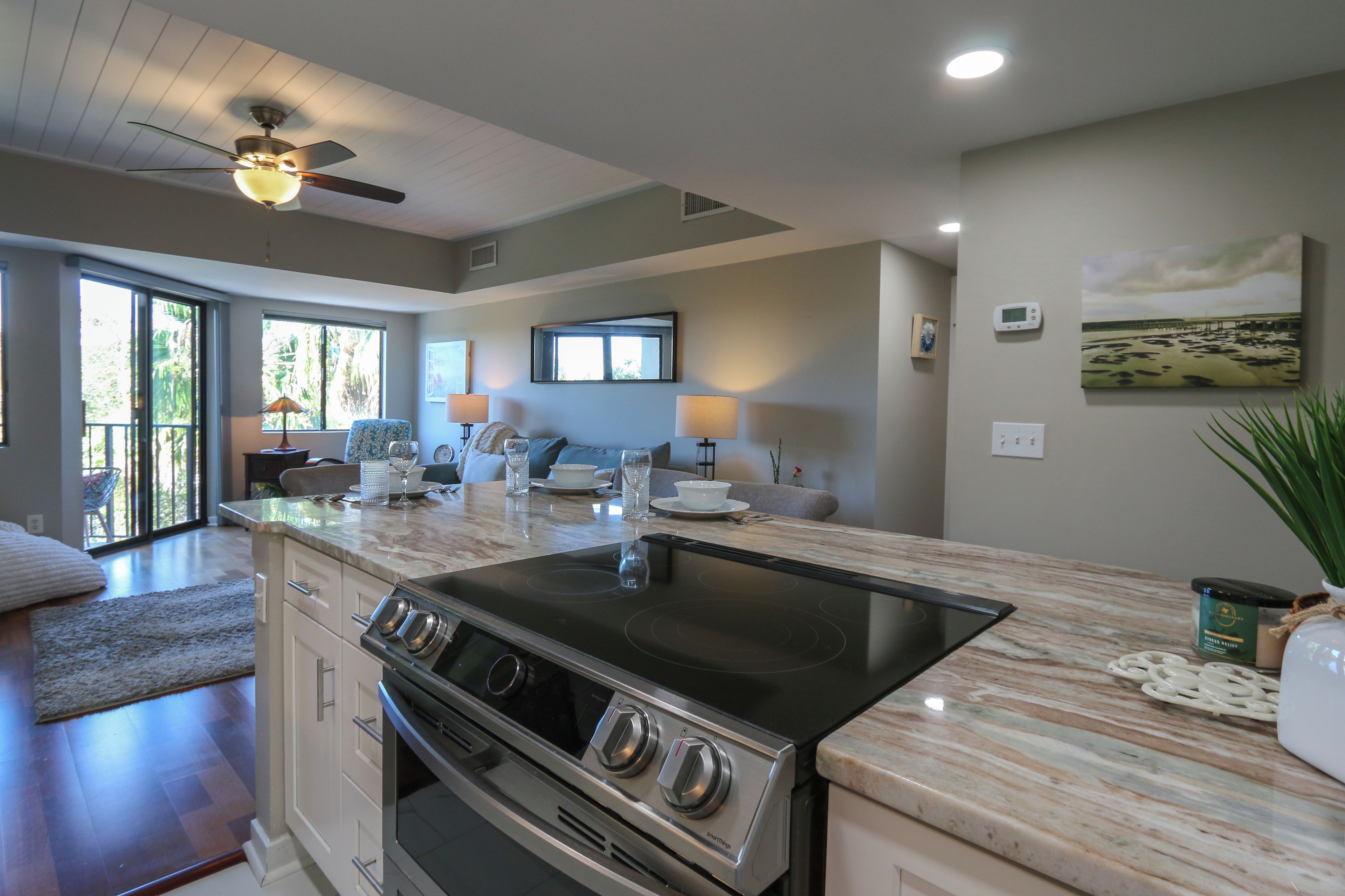 A modern kitchen with a large island, built-in oven, and a ceiling fan.