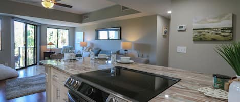 A modern kitchen with a large island, built-in oven, and a ceiling fan.