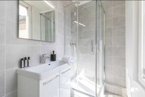 A modern bathroom with a glass shower enclosure, a white vanity with a mirror, and a towel on the counter. - Cosy Apartment -1br/4p- Montreuil - Near Paris (Montreuil)
