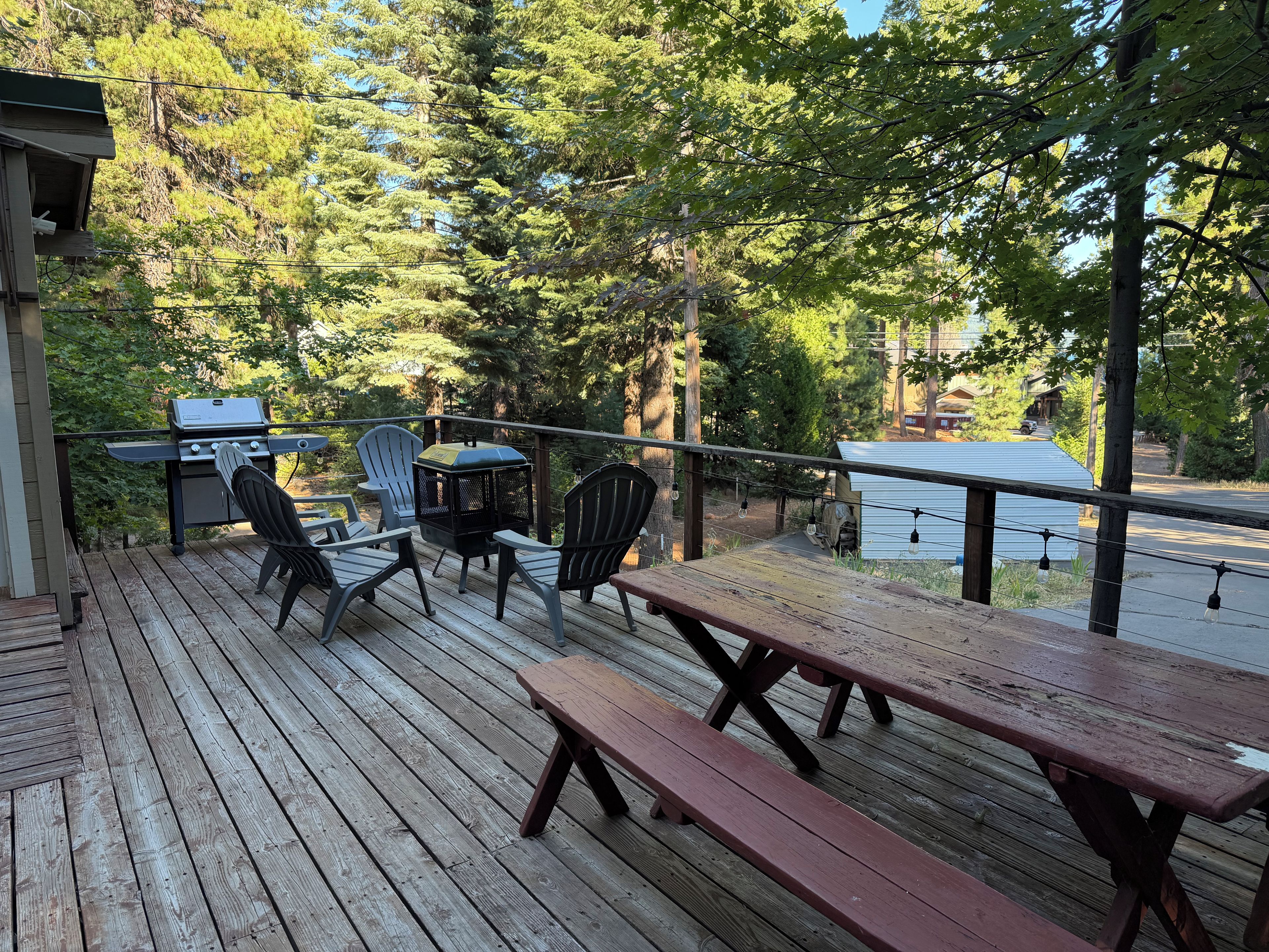 Une terrasse en bois avec des tables et des chaises pour pique-niquer, donnant sur une étendue d’eau.