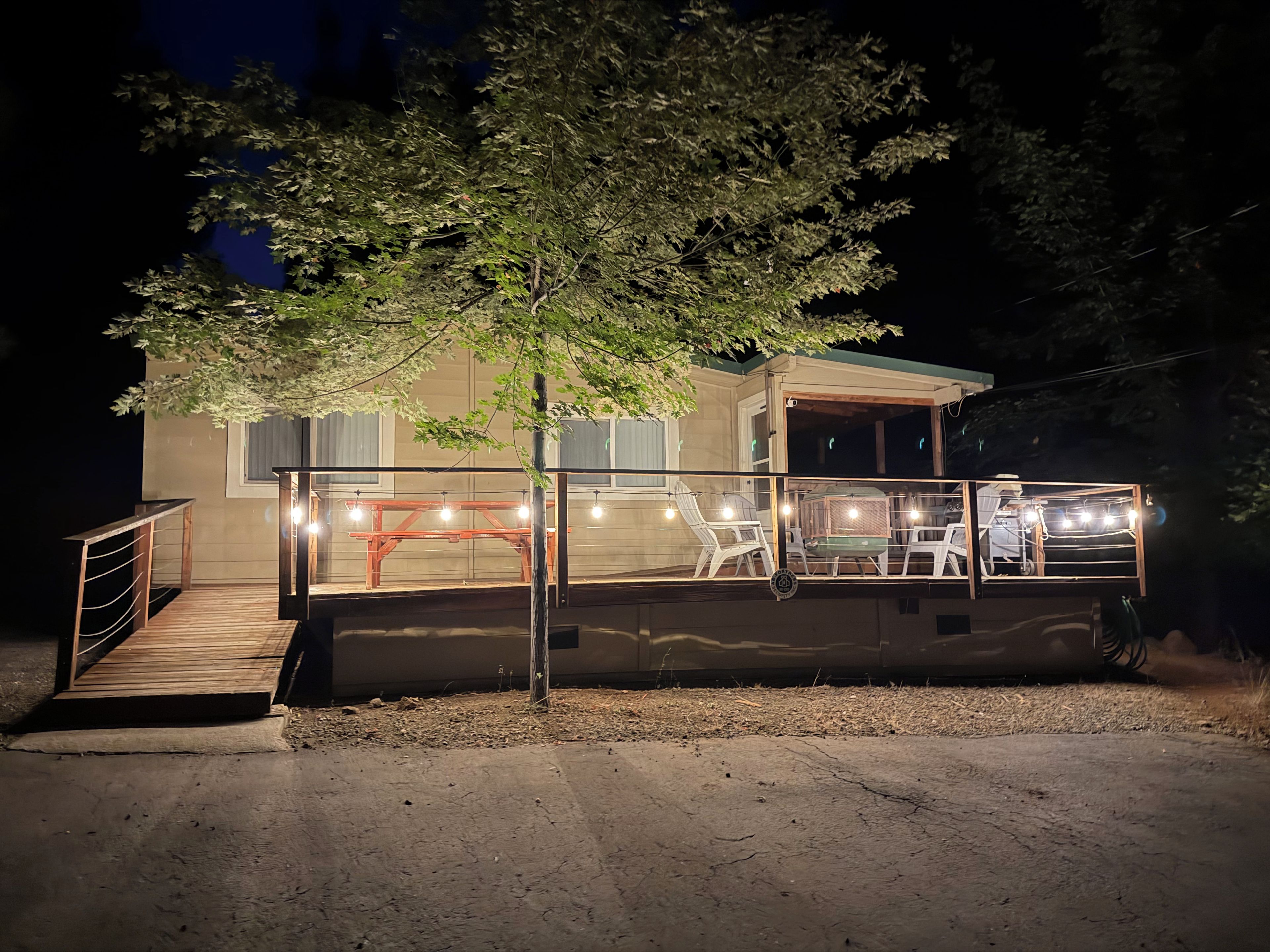 A two-story building with a balcony, outdoor seating, and a tree.