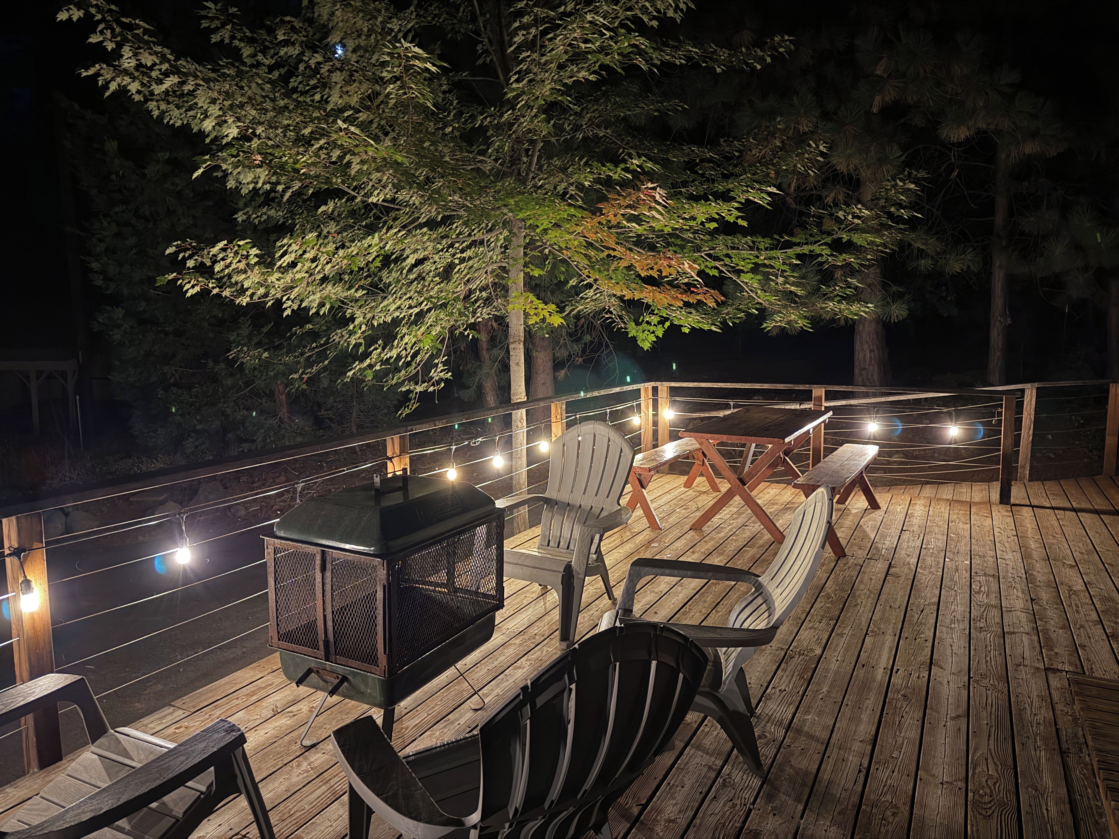 Une terrasse extérieure avec un plancher en bois, un barbecue en métal et des chaises.