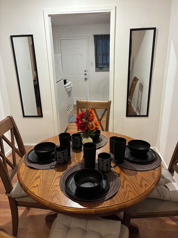 A dining table with black tableware and a vase of flowers, surrounded by chairs and mirrors on the walls. - Copeland (Dallas)