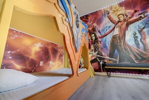 A child's bedroom with a bunk bed, a wall mural of superheroes, and a galaxy-themed wall. - 4BR Themed Home W/Resort Pool Near Disney (Kissimmee)