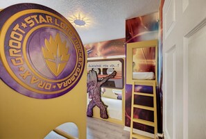 Una habitación con un mural en la pared, literas y una escalera.
