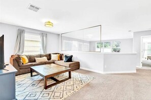 A modern living room with a sectional sofa, a coffee table, and a large window. - Lakefront 5BR Family Resort Pool Home Near Disney (Kissimmee)