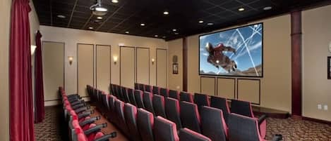 Une salle de conférence avec des rangées de chaises, un grand écran et une moquette à motifs.