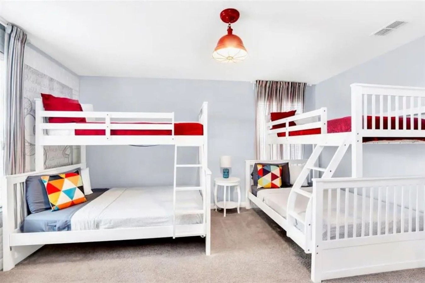 A room with bunk beds, a small table, and a lamp.