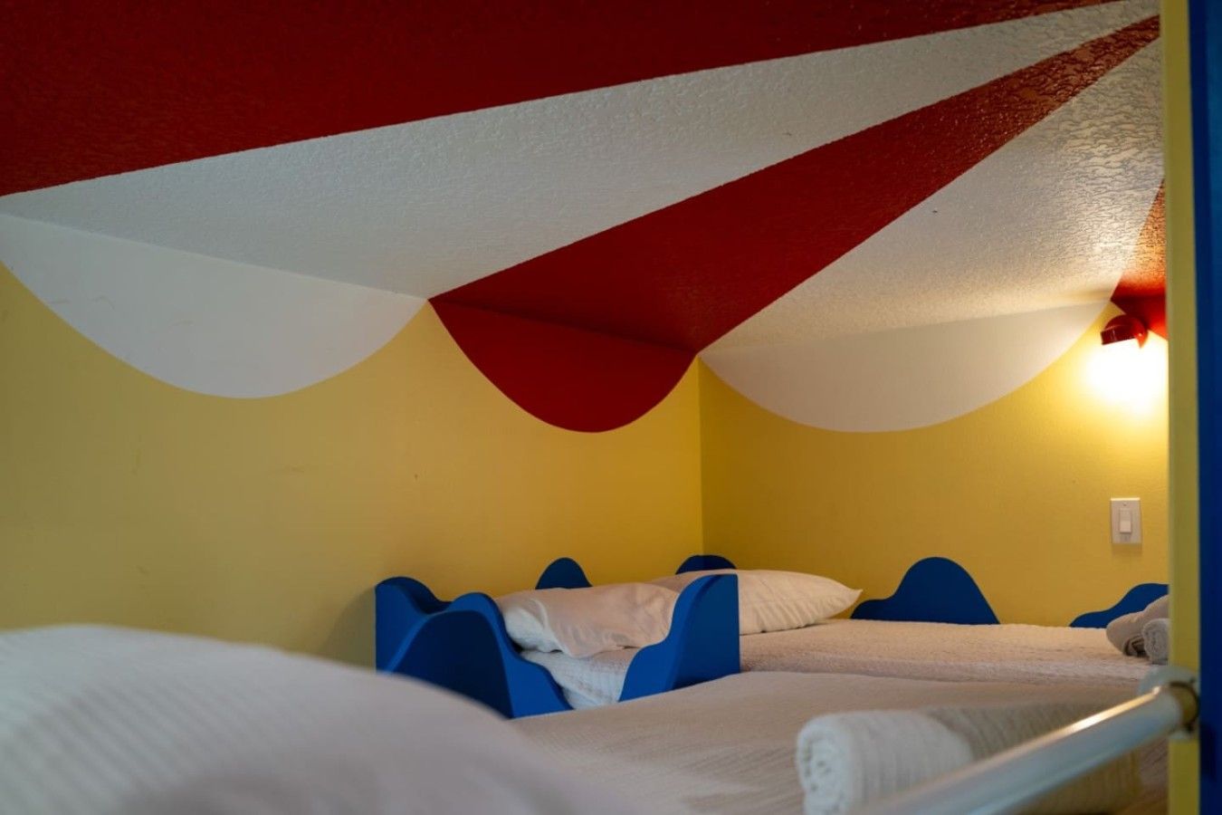 A bunk bed room with two beds, each with blue headboards and white bedding.