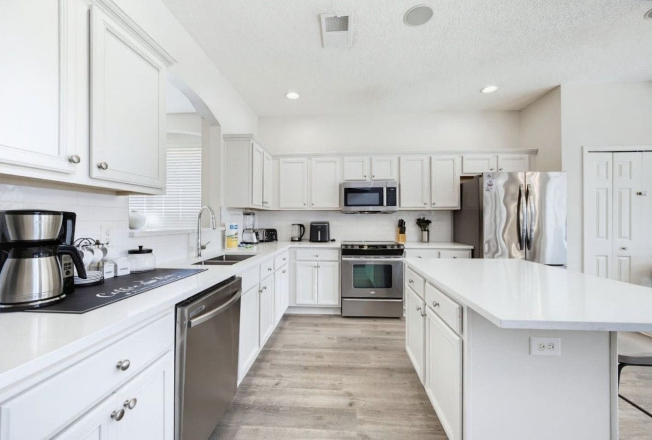 A modern kitchen with white cabinetry, stainless steel appliances, and a central island.