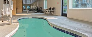 Una piscina con bordo piastrellato, una postazione di salvataggio e sedie a sdraio lungo la parete.