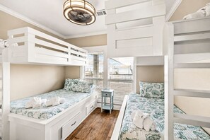 Ein Zimmer mit Etagenbetten, einem kleinen Schreibtisch und einem Fenster mit Jalousien.